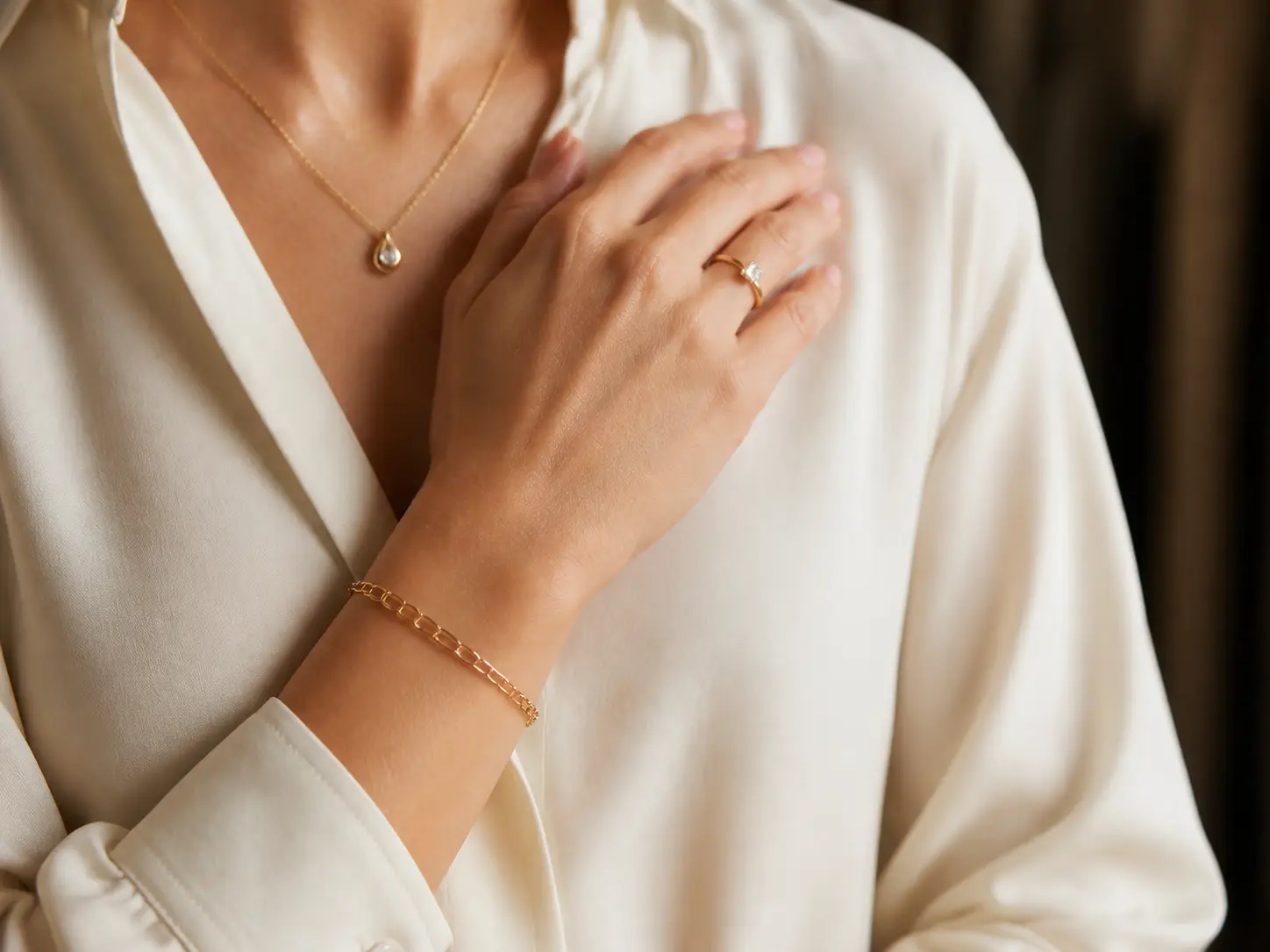 A woman wearing a gold bracelet, ring, and pendant