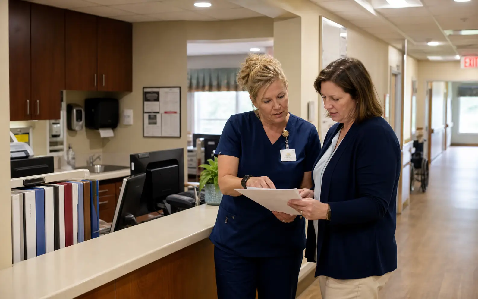 A nurse and senior-care administrator reviewing operations together at a facility nurses' station